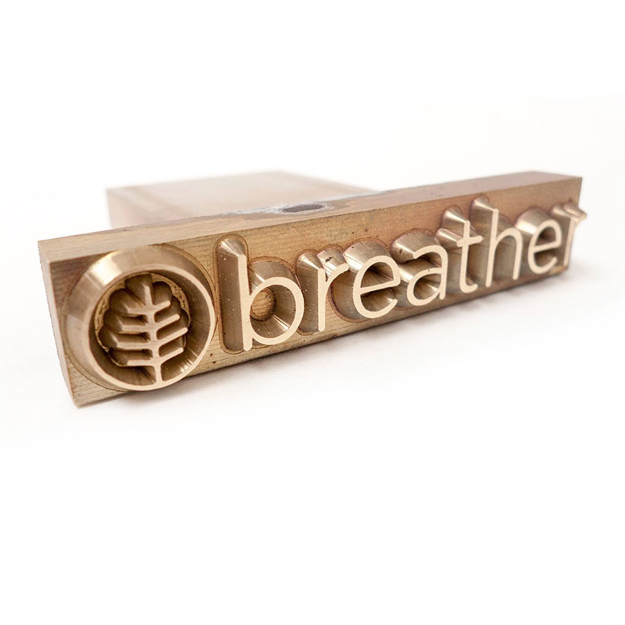 Custom brass stamp used for Breather branding on wooden laptop stand